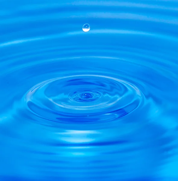 Une goutte d'eau tombant dans l'eau bleue — Photo