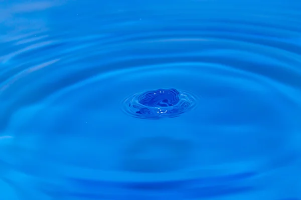 Kapka vody v modré vodě — Stock fotografie