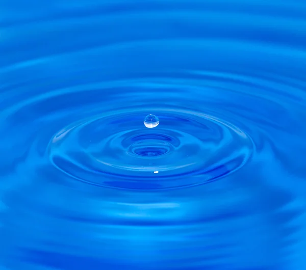 Una goccia d'acqua che cade in acqua blu — Foto Stock