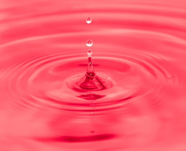 Salpicos de gotas de água no fundo vermelho — Fotografia de Stock