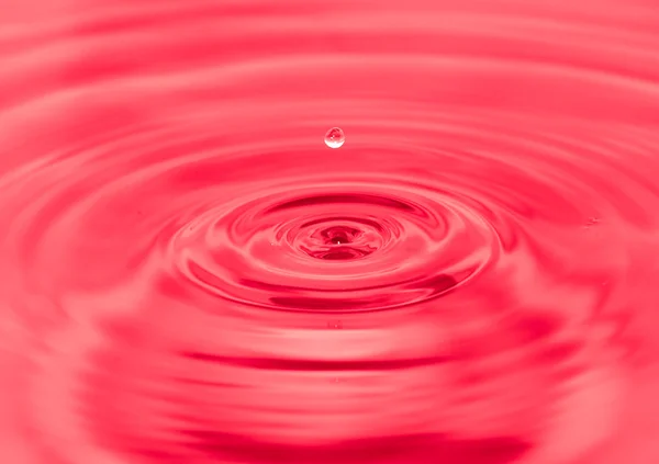Splashing water droplets on red background — Stock Photo, Image