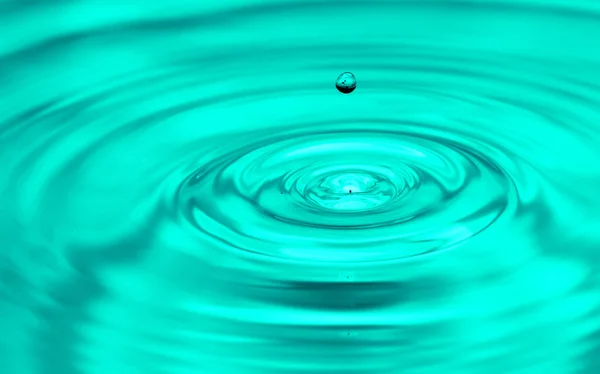 Uma gota de água caindo na água. macro — Fotografia de Stock