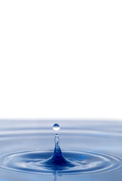 Uma gota de água caindo na água azul — Fotografia de Stock