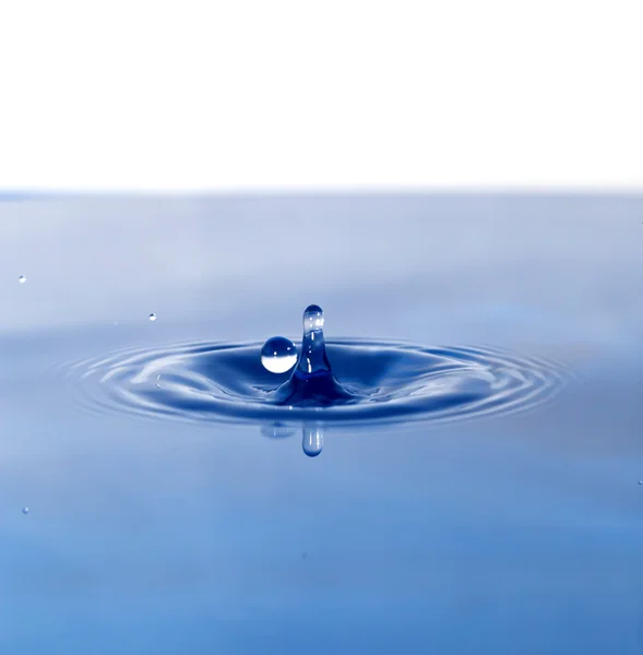 A drop of water falling in blue water — Stock Photo, Image