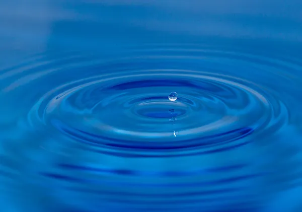 Крапля води, що падає у блакитну воду — стокове фото