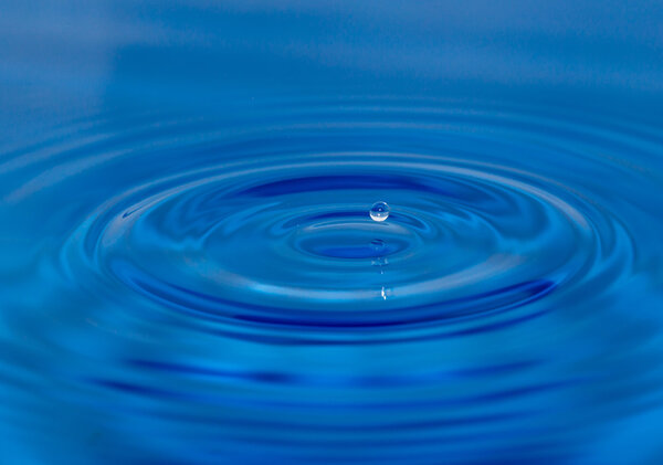 A drop of water falling in blue water