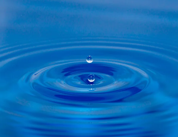 Ein Tropfen Wasser fällt in blaues Wasser — Stockfoto