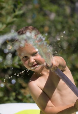 Boy squirting water from a hose clipart