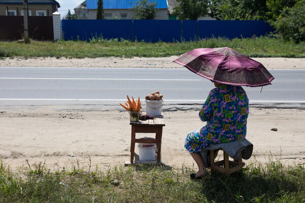 Grandmother sells carrots and potatoes on the road