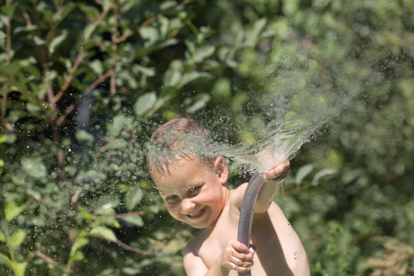 Хлопчик бризкає воду зі шланга — стокове фото