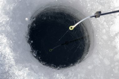 Fishing line in hole drilled in ice clipart