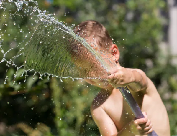 Boy squirting water from a hose — Stock Photo, Image