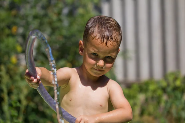 Boy squirting water from a hose — Stock Photo, Image