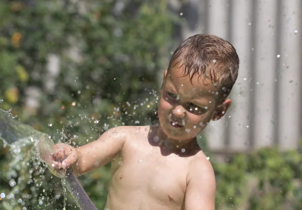 Chlapec stříkat vodu z hadice — Stock fotografie