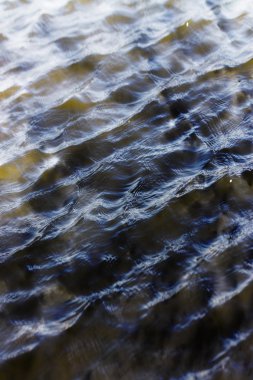 Gökyüzü ve bulutlar su yüzeyine dalga dalga yansıyor.