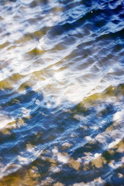 Gökyüzü ve bulutlar su yüzeyine dalga dalga yansıyor.