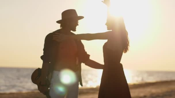 Par i kärlek spelar gitarr och dansar på stranden — Stockvideo