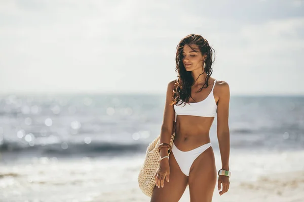 Gebräunte Frau im weißen Bikini am Sommerstrand — Stockfoto