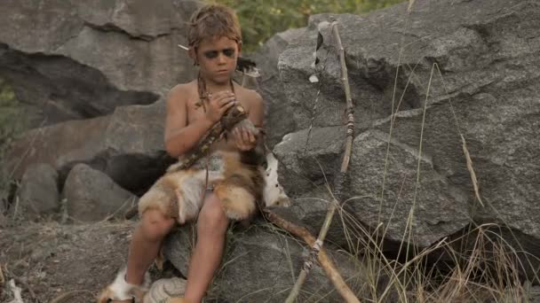 Caveman, manly boy making primitive stone weapon in camp — Stock Video