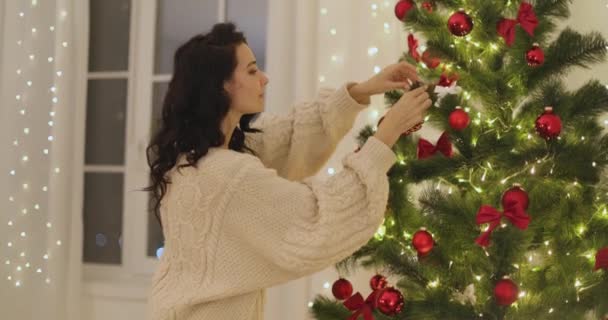 妇女在家中用圣诞树玩具装饰圣诞树 — 图库视频影像