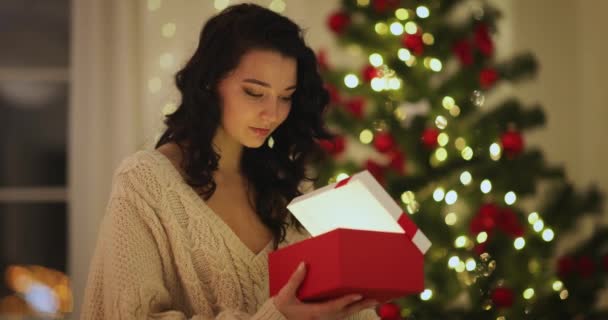 Γυναίκα με παρόν στο κουτί δώρου κοντά χριστουγεννιάτικο δέντρο στο σπίτι — Αρχείο Βίντεο