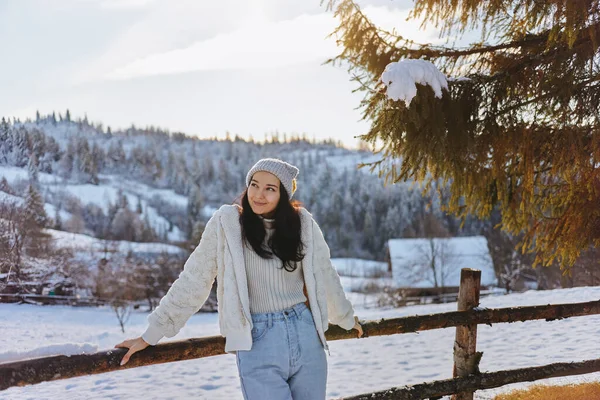 Mujer en invierno Ropa al aire libre contra las montañas nevadas y la aldea —  Fotos de Stock
