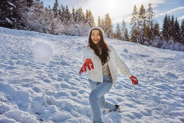 Frau spielt Winterspiel und wirft Schneeball im Gebirgswald — Stockfoto