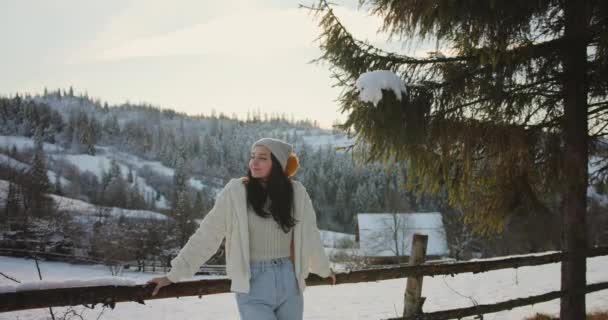 Žena v zimním oblečení Venku proti zasněženým horám a vesnici — Stock video