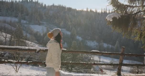 Kvinna i vinter kläder utomhus mot snöiga berg och by — Stockvideo