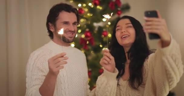 Εορτασμός ζεύγους Πρωτοχρονιά κοντά στο χριστουγεννιάτικο δέντρο στο σπίτι, Video Call ή Selfie στο Smartphone — Αρχείο Βίντεο