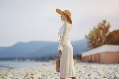 Yaz tatili boyunca arka planda palmiye ağaçlarına karşı şık plaj kıyafeti giyen kadın.