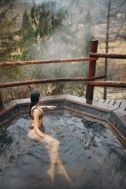 Bikinili bir kadın dışarıda Japon tarzı banyo yapıyor.