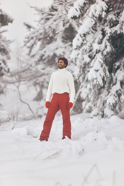 Hombre en traje de esquí y suéter en el bosque nevado durante las vacaciones de invierno al aire libre — Foto de Stock