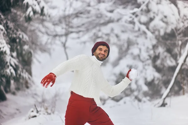 Mann spielt Winterspiel und wirft Schneeball im Gebirgswald — Stockfoto