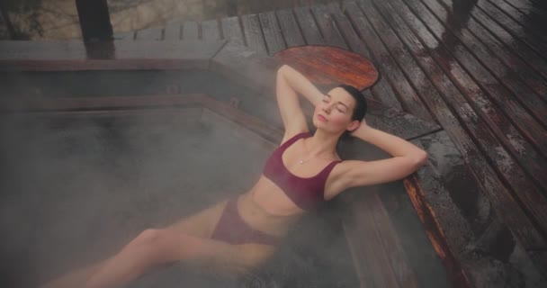 Frau im Bikini badet im Holzbad im Freien — Stockvideo
