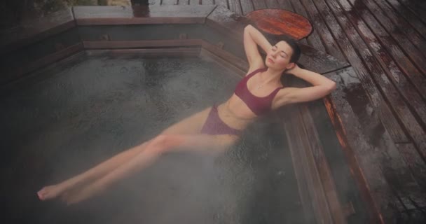 Woman in bikini bathing in wooden bath outdoors — 图库视频影像