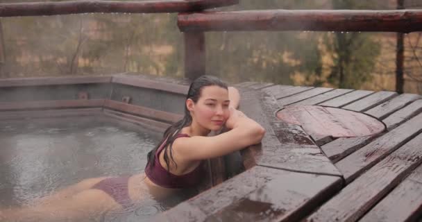 Vrouw in bikini badend in houten bad buiten — Stockvideo