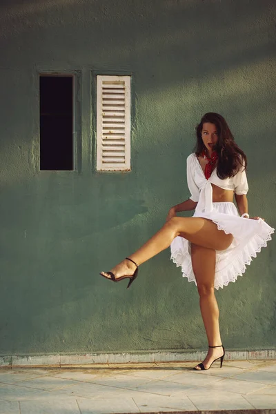 Танцующая женщина в элегантном летнем наряде на открытом воздухе на фоне дома — стоковое фото
