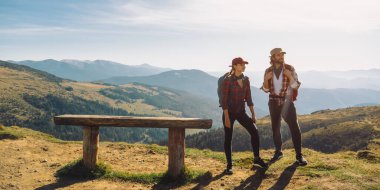 Bir dağın tepesindeki manzara vadisinde sırt çantalı bir çift yürüyüşçü.