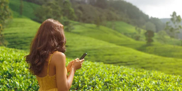 Romantic vlogger traveler woman sharing photos and videos with mobile phone app her travel vacation to famous nature landmark tea plantations in Sri Lanka. Gen Z talent happy girl influencer making