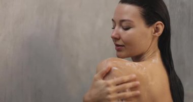 Shower woman washing hair and face while showering with happy smile and water splashing. Beautiful Asian female model at home in shower cabin. High quality slow motion footage 