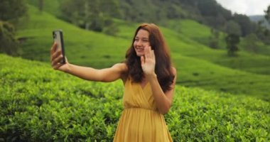 Romantic vlogger traveler woman recording video on mobile phone camera share via app her travel vacation to famous nature landmark tea plantations in Sri Lanka. Gen Z talent happy girl influencer