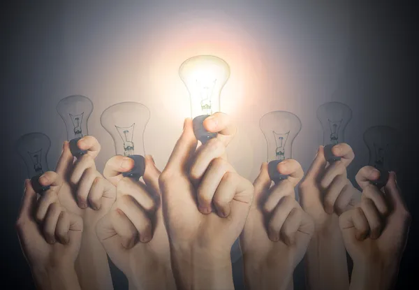 Glowing lightbulb in a hand on gray background. Leadership Conce — Stock Photo, Image