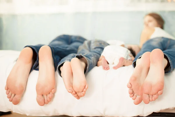 Семья на кровати дома с ногами, показывающими — стоковое фото