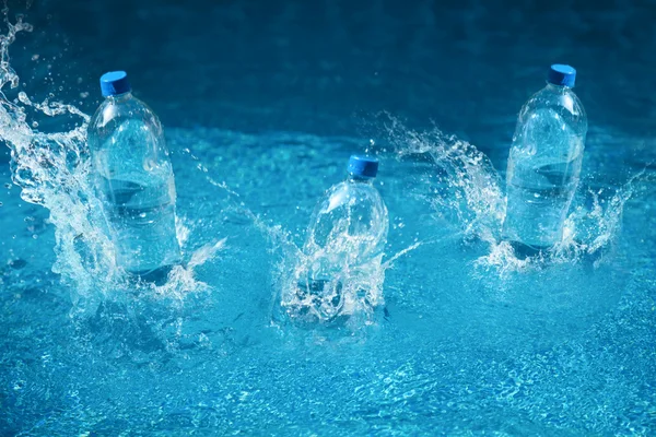 Tres botellas de agua caen con salpicaduras. Disparo en movimiento —  Fotos de Stock