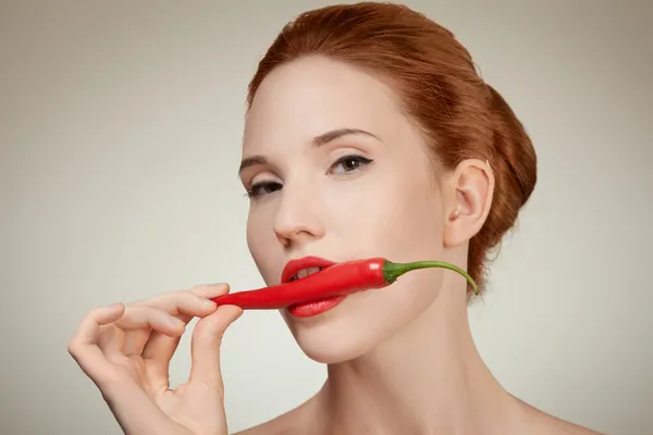 Baharatlı sıcak kırmızı acı biber yeme güzel bir kadın portresi — Stok fotoğraf