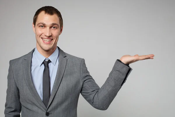 Young business man holding something imaginary in his hand — Stock Photo, Image