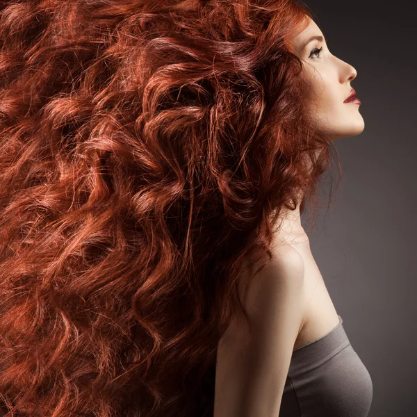 Güzel bir kadın olan gri bir arka plana dayanır kıvırcık saç modeli — Stok fotoğraf