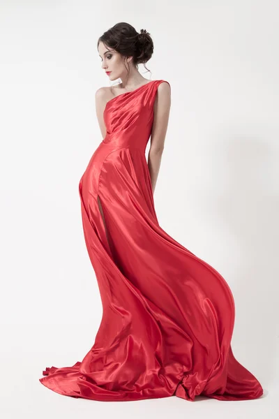 Jong schoonheid vrouw in fladderen rood jurk. — Stockfoto