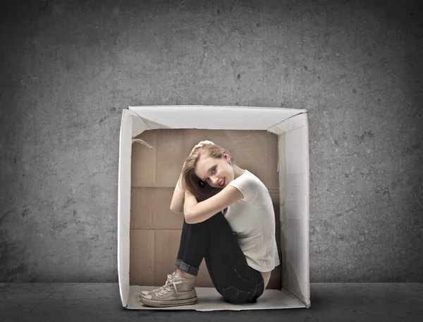 Lächelndes blondes Mädchen kauerte in einer Schachtel — Stockfoto